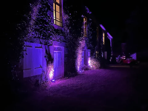 Façade en pierre mise en lumière en violet de nuit