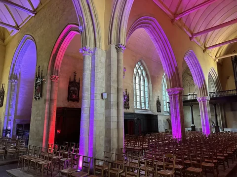 Arches et colonnes d’une église mises en lumière en rose et violet