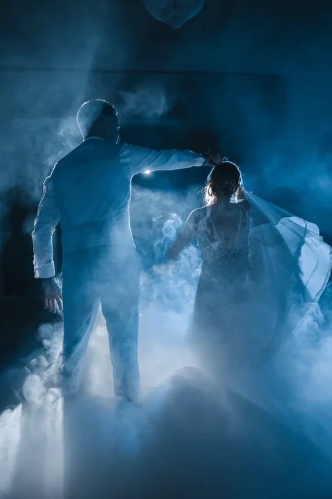 Première danse des mariés dans la brume et une lumière bleue