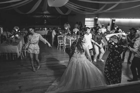 Photographie en noir et blanc de la mariée et des invités sur la piste de danse