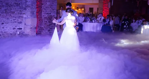 Mariés lors de leur ouverture de bal avec fumée lourde et éclairage bleu et blanc