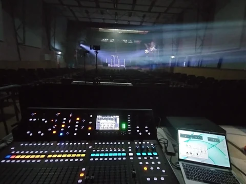 Console de régie et ordinateur face à une scène éclairée en salle