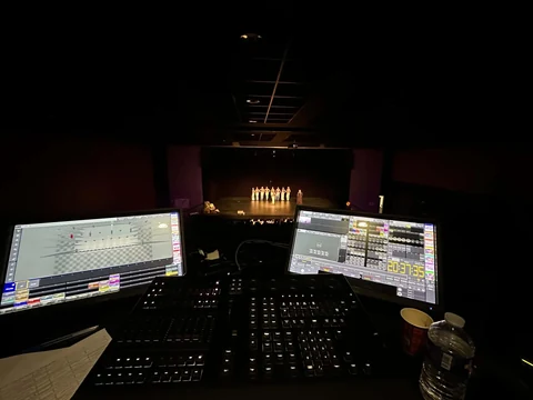 Console et écrans de contrôle lumière pendant un spectacle en salle