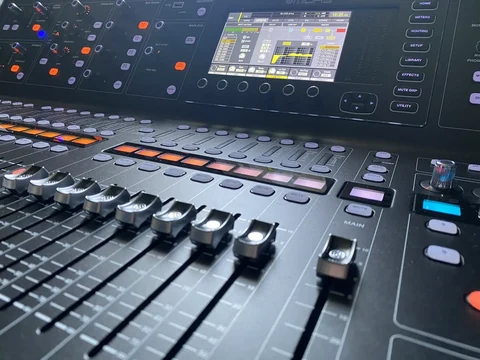 Vue rapprochée d’une console de mixage numérique Midas, avec ses faders et son écran de réglage