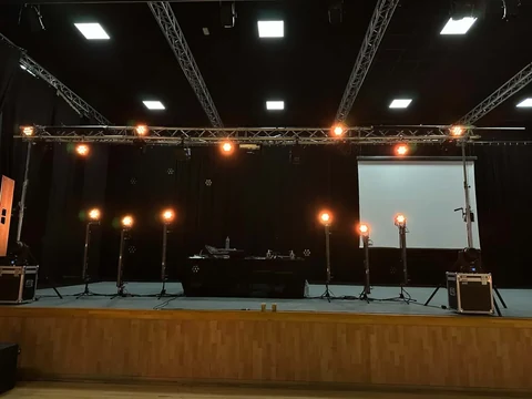 Installation scénique avec projecteurs, structures et écran en salle